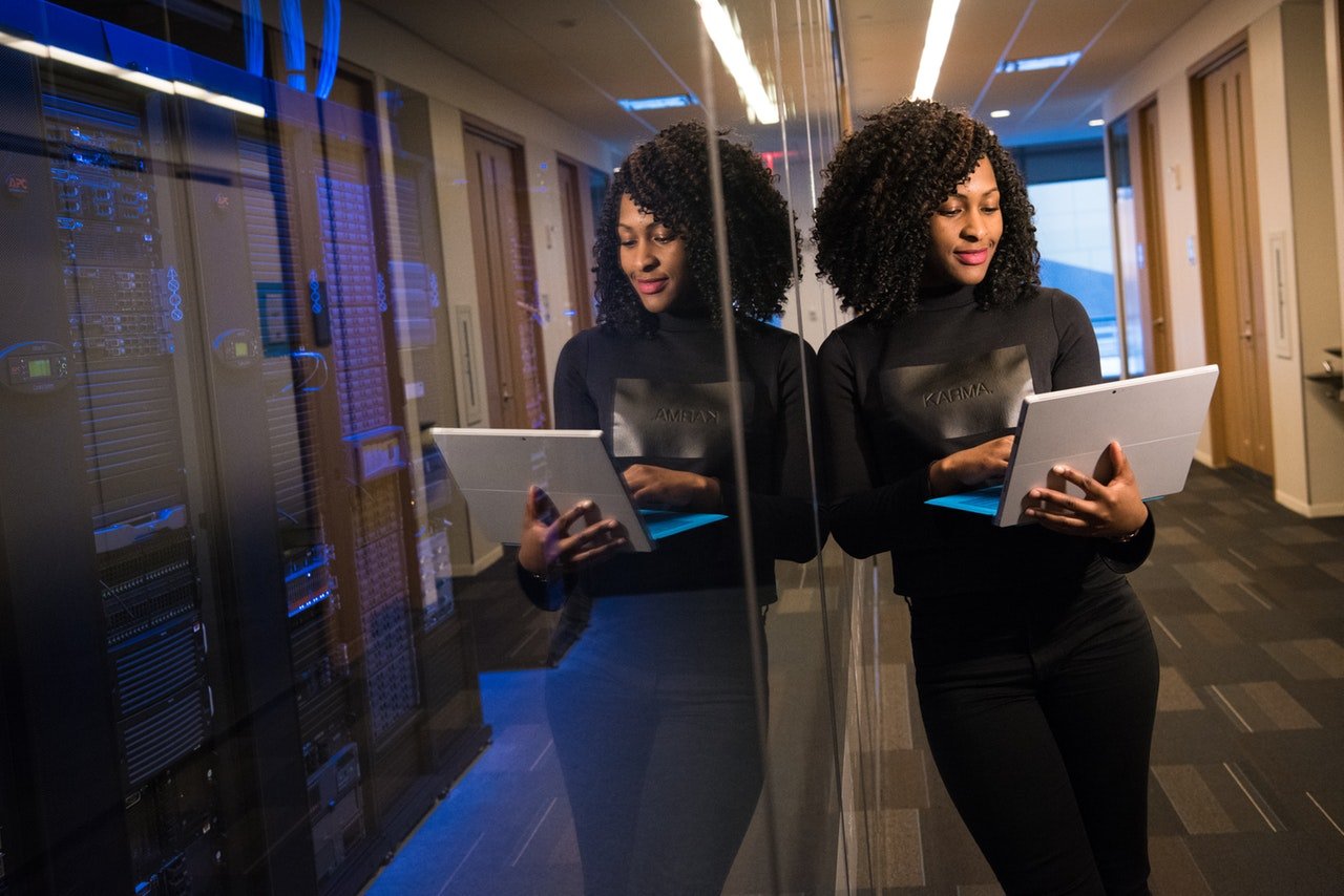 Woman holding a laptop leaning on a glass wall